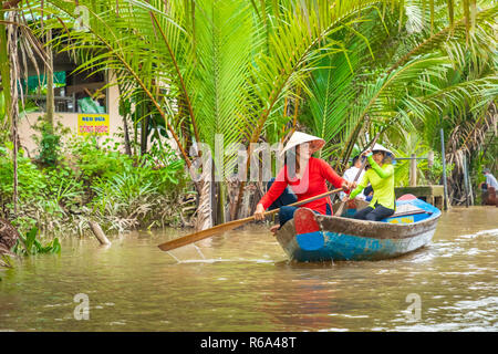 MY THO, VIETNAM - November 24, 2018: Vietnamesische Frauen in der traditionellen Vietnamesischen cap Paddel ein kleines Boot mit Touristen auf dem Mekong Fluss in meinem Th Stockfoto