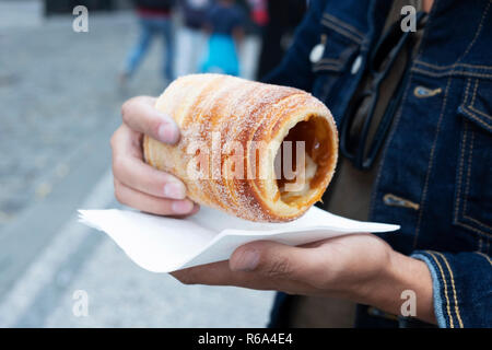 Nahaufnahme eines yougn kaukasischen Mann essen eine trdelnik, einem typischen Spieß Kuchen, in der Altstadt von Prag, Tschechische Republik Stockfoto