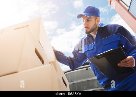 Männliche Arbeiter in der Nähe von Karton Holding Zwischenablage Stockfoto