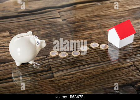 Euro Münzen zwischen den Sparschwein und Haus Modell Stockfoto