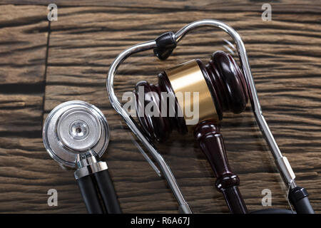Stethoskop und Hammer auf hölzernen Schreibtisch Stockfoto