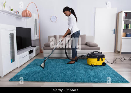 Frau Reinigung Teppich mit Staubsauger Stockfoto