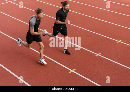 Image der Jungen zwei Zwillinge Sportler Brüder im Stadion im Freien läuft. Stockfoto