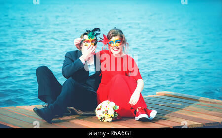 Glückliches Paar in der Maskerade Masken gegen einen türkisfarbenen See Stockfoto