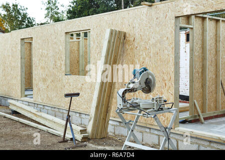 Ein Fachwerkhaus ist mit OSB Platten schnittholz Platten Form gebaut. Carpenter's sah in den Vordergrund chop Stockfoto