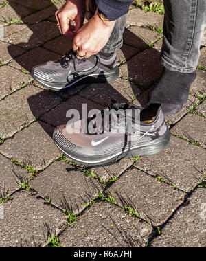 Eine Frau, die Band ihre Schnürsenkel auf einem Paar grau Nike Zoom Trainer Gyakusou Fliegen Stockfoto