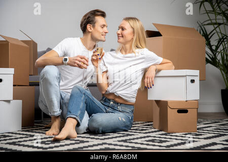 Bild von glückliches junges Paar mit Champagner Gläser sitzen unter Kartons Stockfoto