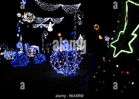 Leuchtende Schneeflocken und helle Streifen auf dunkle, romantische Nacht Himmel Hintergrund. Schönen Weihnachtsmarkt und Dekorationen im Stadtzentrum. Stockfoto