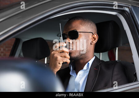 Mann sitzt im Auto mit Walkie Talkie Stockfoto