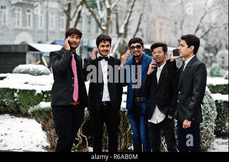 Gruppe von 5 indische Studenten in Anzügen stellten im Winter im freien Tag und sprechen am Telefon. Stockfoto