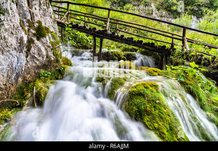 Wasserfall unter einer Fußgängerbrücke in Nationalpark Plitvicer Seen, Kroatien Stockfoto