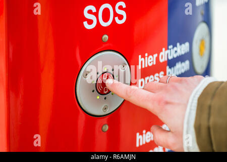 Frau drücken SOS-Taste im Bahnhof Stockfoto