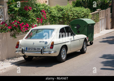 Santa Ponsa, Mallorca, Spanien - 24. Juli 2013: Retro Car MG BGT ist in der Nähe einer Wand mit Blumen und Palmen Blätter geparkt. Stockfoto