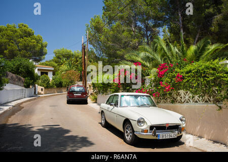 Santa Ponsa, Mallorca, Spanien - 24. Juli 2013: Retro Car MG BGT ist in der Nähe einer Wand mit Blumen und Palmen Blätter geparkt. Stockfoto