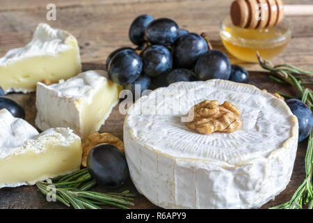 Camembert Käse mit Trauben, Honig Walnüsse und Rosmarin auf Holz Schneidebrett. Nach oben Schließen Stockfoto