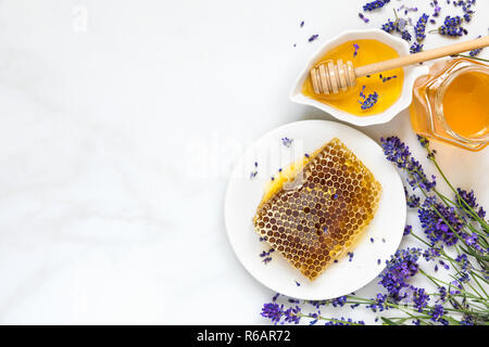 Honig mit Lavendelblüten und Waben auf weißem Marmortisch. gesundes Essen. Ansicht von oben mit der Kopie Raum Stockfoto