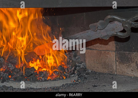 Die Smith geschickt heizt ein Klumpen aus Metall für die Gestaltung in einem Messer Stockfoto