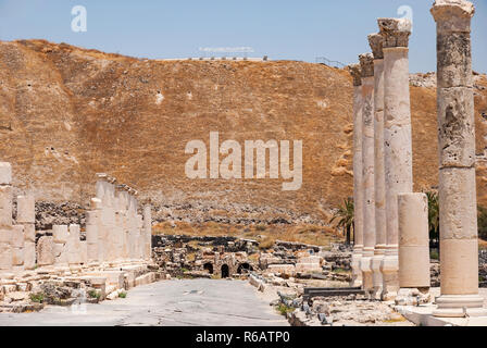 Palladius Street und Spalten in der antiken römischen Stadt Beit Shean Mit tel Beit Shean im Hintergrund Stockfoto