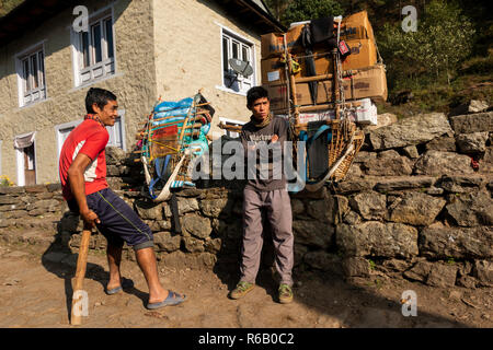 Nepal, thado Koshi Gaon, junge Torhüter neben ihren schweren packs Auf dem Weg nach Namche Bazaar ruhen Stockfoto