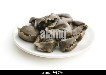 Tintenfisch tortellini Nudeln auf dem Teller auf weißem Hintergrund. Stockfoto