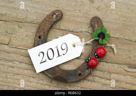 Das neue Jahr Karte mit Hufeisen, blätterte Kleeblatt und Marienkäfer an Holz- Hintergrund Stockfoto