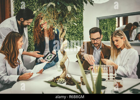 Clevere progressive junge Ingenieure arbeiten an digitalen Tablet auf einer ökologischen Bauvorhaben im Büro, reden über einige grüne Projekt. Stockfoto