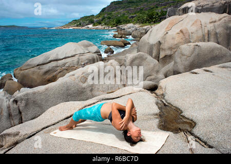 Yoga auf Felsen in sechs Richtungen Zil Pasyon Luxus Hotel. Felicite Island Seychellen. Stockfoto