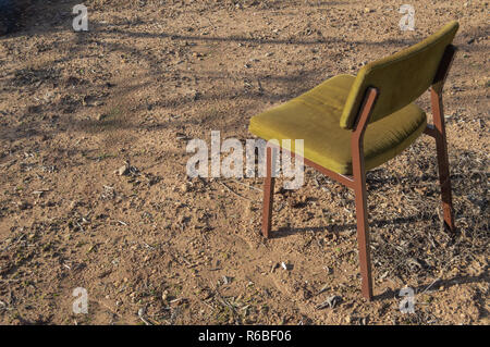 Leer und einsam Stuhl vor der Sonne in der Wüste. Alte vintage Stuhl in einem Moor an einem sonnigen Tag verloren. Konzept der warten, verlassen oder Einsamkeit. Stockfoto