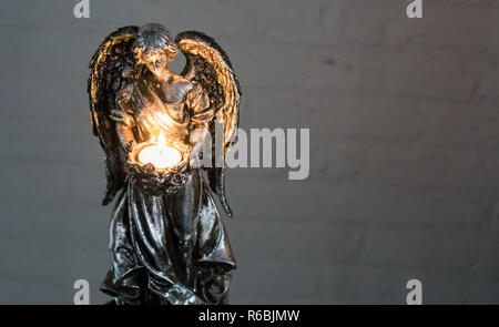 Weihnachten oder spirituellen Tradition, ein silberner Engel Skulptur Holding ein brennendes Licht Stockfoto