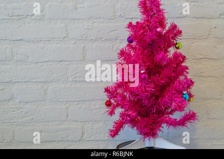 Rosa künstliche geschmückten Weihnachtsbaum vor eine weiße Wand Stockfoto