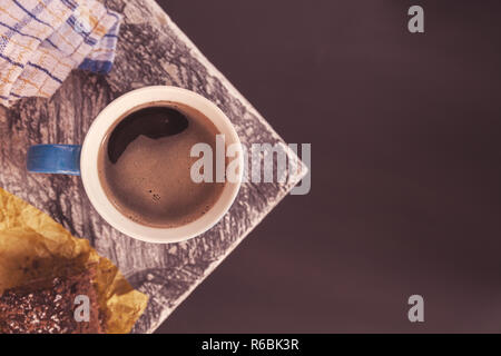 Chocolate Brownie bestreut mit Kakao und Kokosnuss im Hintergrund mit einem kaffeebecher an der Ecke einen Tisch in der Nähe eines Fensters. Foto Stockfoto