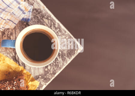 Chocolate Brownie bestreut mit Kakao und Kokosnuss im Hintergrund mit einem kaffeebecher an der Ecke einen Tisch in der Nähe eines Fensters. Foto Stockfoto