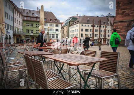 Freiburg im Breisgau, Deutschland - 31. Dezember 2017: Tabelle: ein Cafe, vor dem sich die Leute warm gekleidet zu Fuß auf den gepflasterten Platz der Cathedra Stockfoto