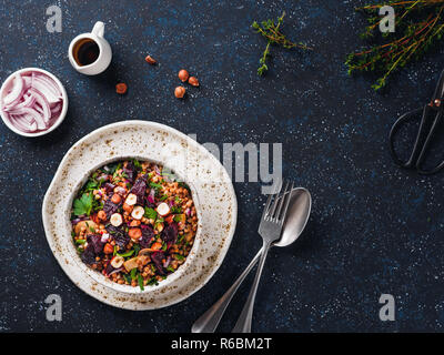 Warme Buchweizen und Rote-Bete-Salat auf dunklem Hintergrund. Vegetarische Ernährung Idee und Rezept-Salat mit roter Bete, Buchweizen, Champignons, Zwiebeln, frischen Kräutern, Haselnuss. Ansicht von oben oder flach-legen. Kopieren Sie Platz für Text Stockfoto