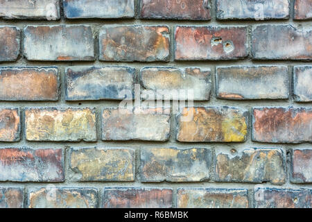 Fragment einer Wand aus alten blau-roten Ziegelsteinen für den Einsatz als Hintergrund. Stockfoto