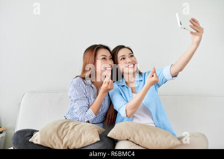 Nahaufnahme, Porträt von zwei aufgeregt Freundinnen mit Mobiltelefonen, Lachen. Gerne fröhliche weibliche Freunde Ruhe zu Hause, genießen Sie Gespräche, Spaß zu haben. Stockfoto