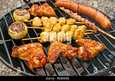 Barbecue mit Chicken Wings, Bratwurst, Fleischspieße und Schinken Stockfoto