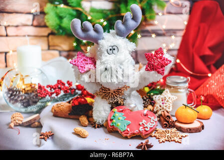 Weihnachten Dekor - weiße Spielzeug Rentier mit Sterne in den Händen, tangerins, Cookies und hellen Stern bokeh Stockfoto
