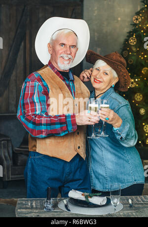 Senior Paar feiert das neue Jahr mit Sekt, Beleuchtung und Weihnachtsbaum auf Hintergrund Stockfoto
