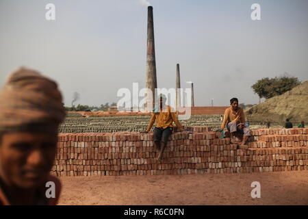 Arbeiten an einem Backstein Feld in Dhaka, Bangladesh. Arbeit mit Kindern sind an den Backstein Felder unten in der Dämmerung mit ungesunden Zustand, wie auch die Lohnkosten nicht auf Minimum Standard entsprechen. Bangladesch Platz am schnellsten wachsende Land der Welt die Verstädterung rapide an. Trotz der Ziegel ist der Schlüssel Materialien Gebäudestruktur als große Zahl von Backstein Yards zu bauen in der Landwirtschaft landet die Verringerung der landwirtschaftlichen Produktion statt. Die meisten der Backstein yards Holz, Kohle auf rohe Ziegel brennen als CO2-Emissionen. Stockfoto