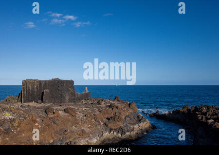 Shoreline, Los Cancajos. La Palma. Die Lava Rock Küsten Relief, die typisch für die Insel sind. Die Reste einer alten Turm auf einem Stück Land Masse ins Meer vorspringenden bleiben. Stockfoto