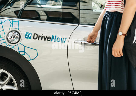 Deutschland, Berlin, 05. September 2018: eine Person öffnet die Tür zu einer gemieteten BMW-Elektroauto von einer Firma namens DriveNow. Autovermietung erfolgt durch eine mobile Anwendung auf einem Mobiltelefon. Stockfoto