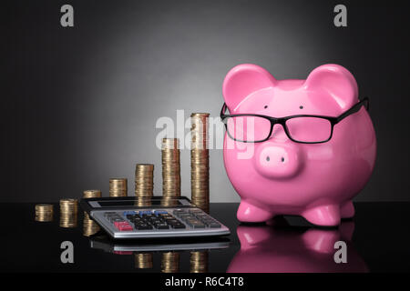 In der Nähe von piggy Bank, Rechner und gestapelte Münzen Stockfoto