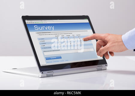 Geschäftsmann füllen Online Umfrage Formular auf Hybrid Laptop Stockfoto