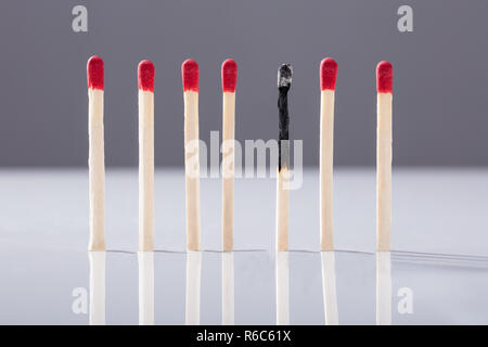 Verbrannt Streichholz getrennt durch rote Streichhölzer Stockfoto