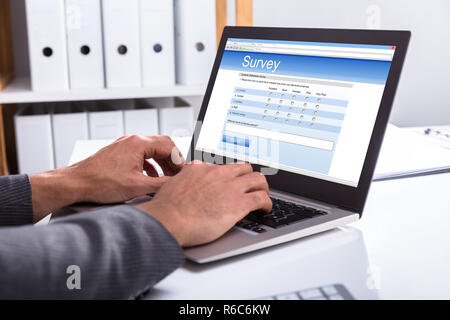 Unternehmer füllen Online Umfrage Formular auf Laptop Stockfoto