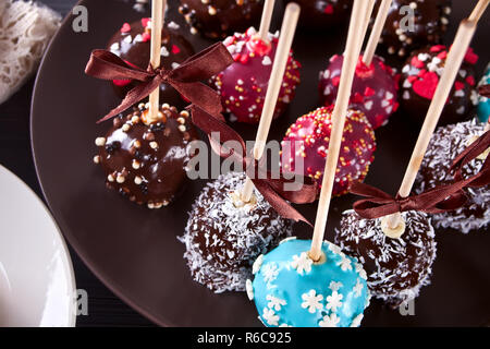 Verschiedene Kuchen Pops mit weißer und dunkler Schokolade auf einen hölzernen Tisch dekoriert Stockfoto