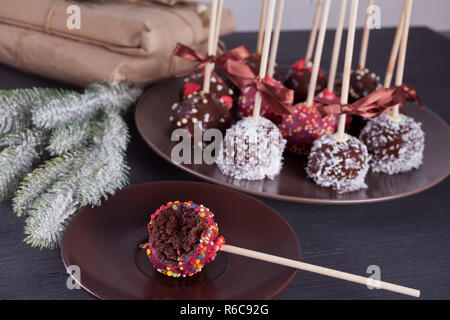 Verschiedene Kuchen Pops mit weißer und dunkler Schokolade auf einen hölzernen Tisch dekoriert Stockfoto