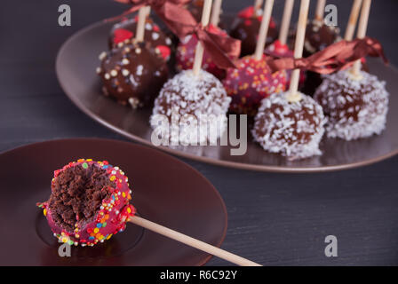 Verschiedene Kuchen Pops mit weißer und dunkler Schokolade auf einen hölzernen Tisch dekoriert Stockfoto