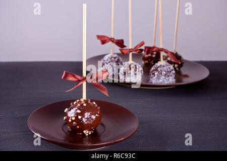 Verschiedene Kuchen Pops mit dunkler Schokolade auf einen hölzernen Tisch dekoriert Stockfoto